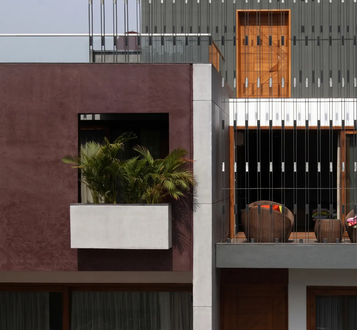 Burgundy textured façade with planted balcony