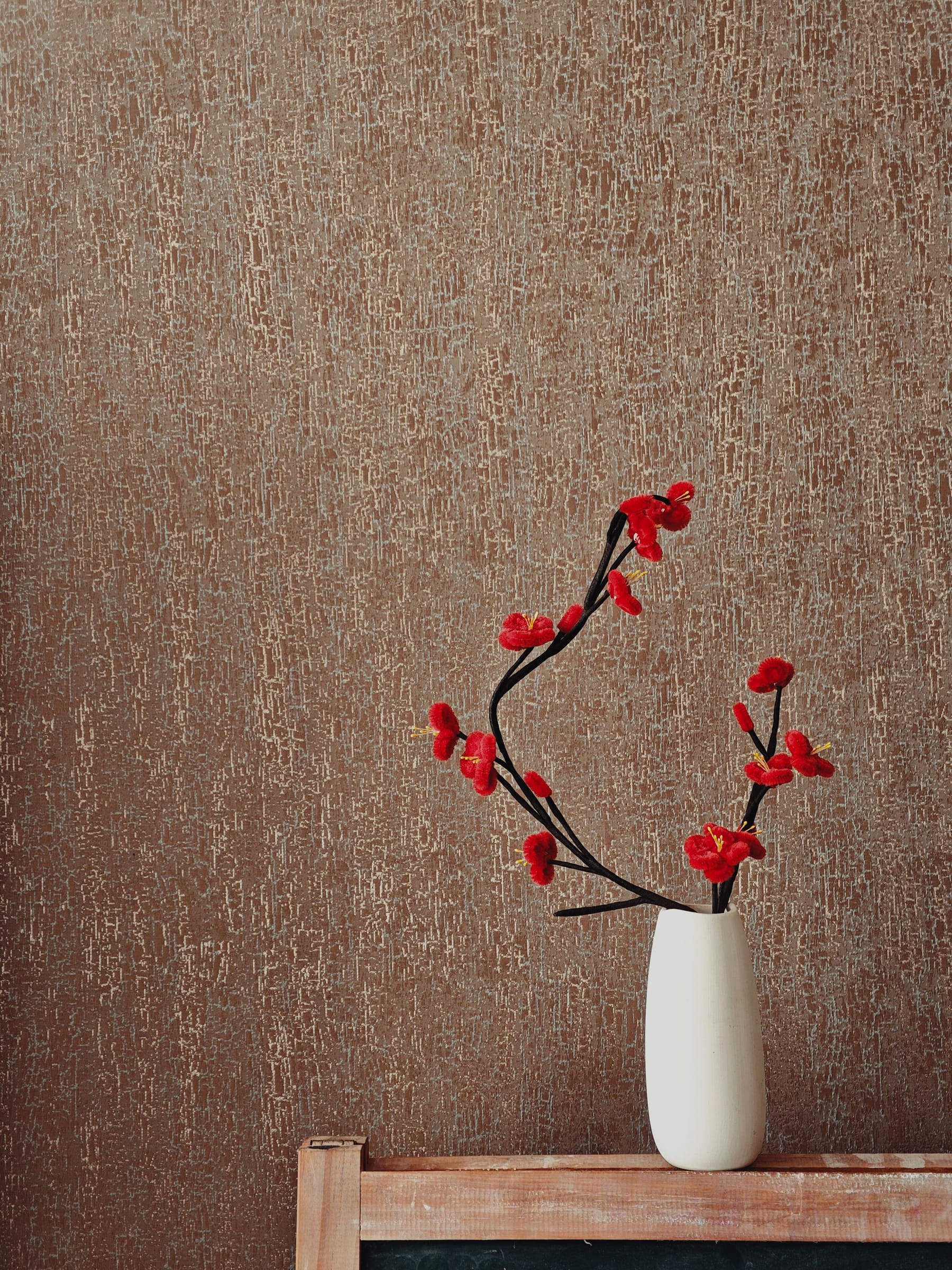 Brown textured wall behind a flower vase